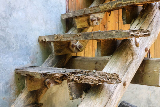 Weathered wooden ladder against rustic wall with chipped steps, rough timber texture, and aged construction detail