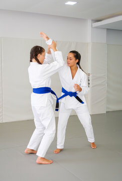 Two Brazilian jiu jitsu students practice a standing self defense entry, making hand and forearm contact before establishing an armlock