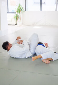 A Brazilian jiu jitsu instructor and student practice a juji gatame armbar, with the attacker holding the wrist and placing her legs across the upper body