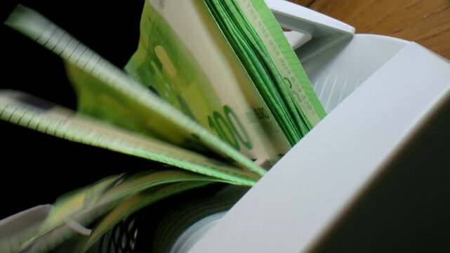Extreme macro shot of 100 Euro banknotes in a rapid cash counting machine