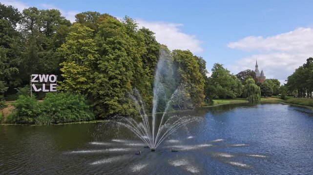 Water fountain spraying in the city moat featuring the large ZWOLLE city sign and green park landscape in Zwolle, Netherlands on 23 August 2026.