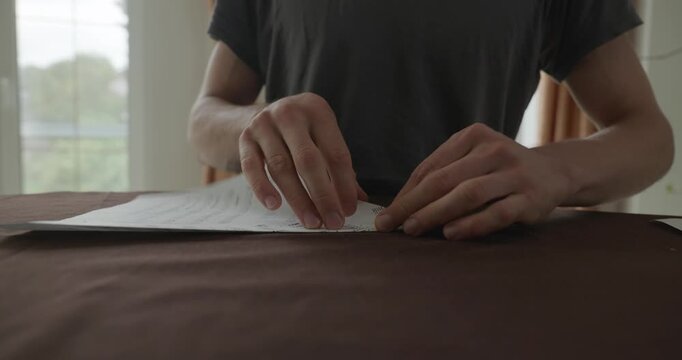 Close-up male hands fold sheet of paper making paper airplane. 4K 10-bit