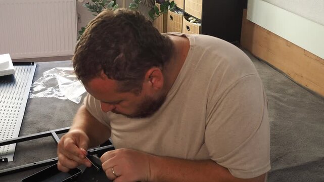 The man is repairing the shelf. Worker assembling furniture
