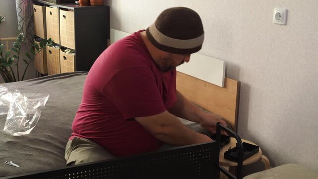 The man is repairing the shelf. Worker assembling furniture
