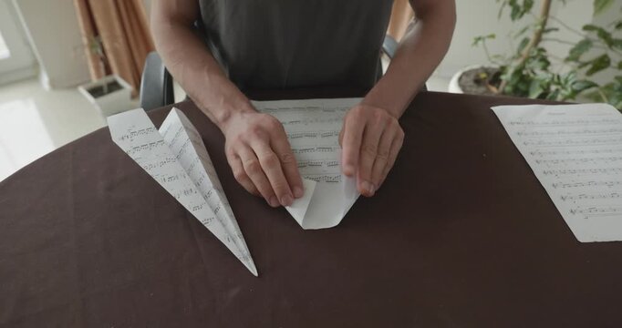 Close-up male hands fold sheet of paper making paper airplane. 4K 10-bit