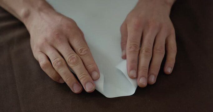 Close-up male hands fold sheet of paper making paper airplane. 4K 10-bit