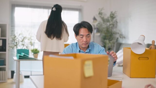 Asian businessman packing personal belongings in box after being laid off from job