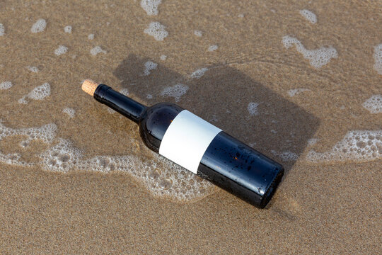 Message in a bottle with blank label on wet sandy beach