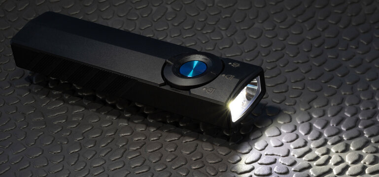 Bright white LED glowing on a black rechargeable flashlight