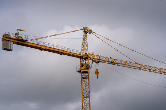 Low angle view of a yellow tower crane against a dramatic overcast sky