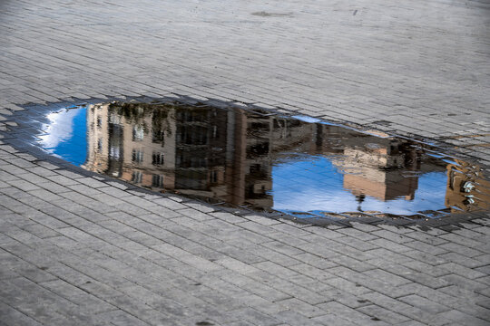 The street is reflected in a rain puddle on an autumn day