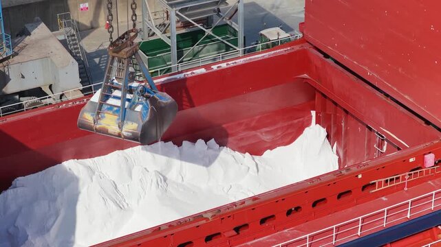 Industrial Crane Unloading White Cargo From a Large Ship Into a Container Hopper