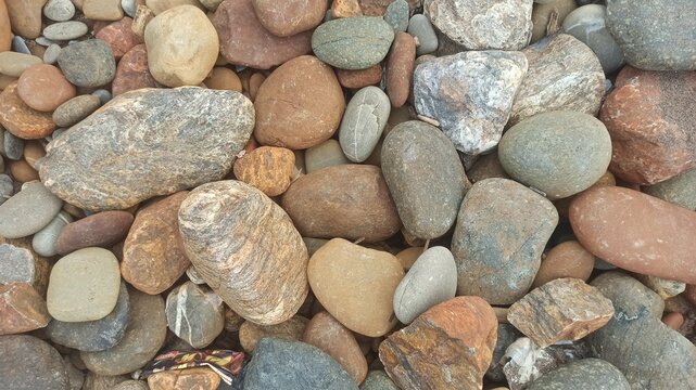 Smooth river rocks in gray, beige, and brown. Natural texture and abstract background.
