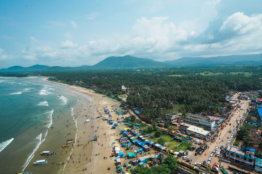A breathtaking top view of the scenic Gokarna coastline in Karnataka, India, featuring a beautiful sandy beach, turquoise sea, dramatic rocky shoreline, and lush green landscape.
