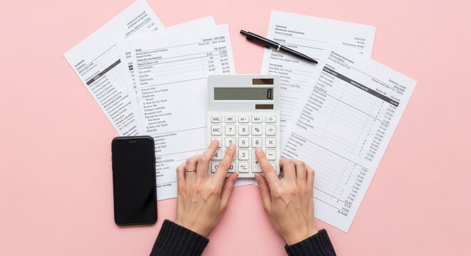Hands using calculator with financial documents and phone
