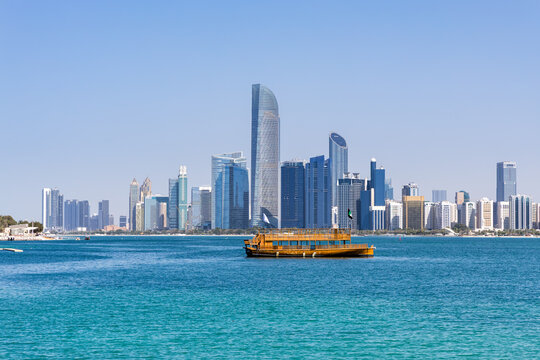 Abu Dhabi skyline with skyscrapers and Dhow boat at sea in Abu Dhabi, United Arab Emirates