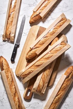 Sourdough Baguettes in Kraft Packaging on Wooden Cutting Board Food Product Photography