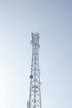 A tall metal telecommunication antenna tower standing against a clear light blue sky background for wireless network and mobile connection concepts. High Quality Photo