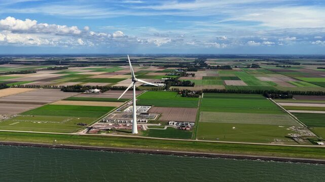 Aerial view of a wind turbine and electrical substation in the Netherlands.