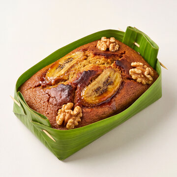 Gula Melaka Banana Cake in Fresh Green Banana Leaf Box on Minimalist Studio White Background