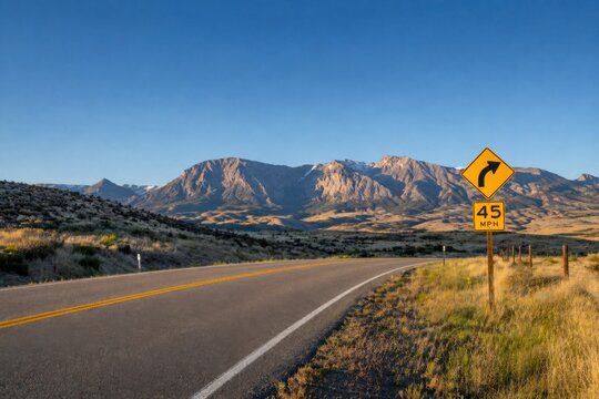 Scenic highway winding through mountainous terrain with a warning sign for wildlife crossing and speed limit of 45 MPH in a rural landscape
