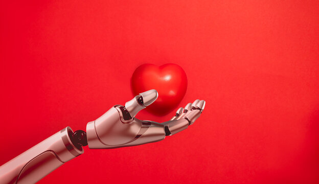 Robotic hand gently holds a red heart. Human-centered artificial intelligence, responsible technology, empathy, ethical innovation, wellbeing and supportive human-machine collaboration concept.