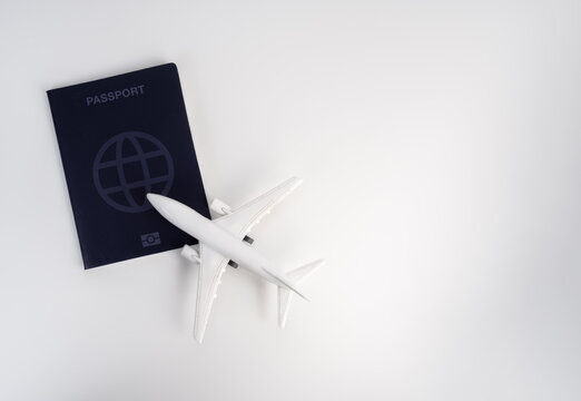 Passport and airplane model arranged on clean white background with space. International travel planning, global mobility, flight booking, overseas journeys and modern aviation transportation concept.