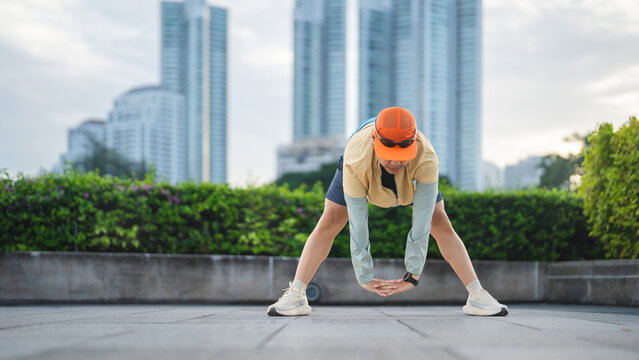 Adult asian man runner stretching and warm up at outdoors public park in city