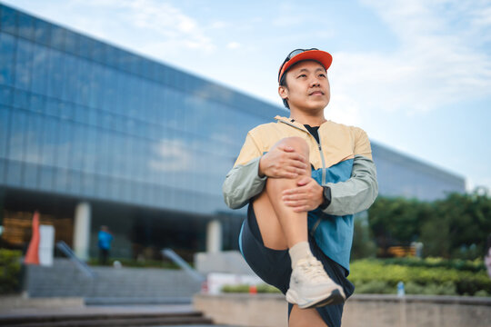 Adult asian man runner stretching kneel and leg wear sports outfit training for running marathon challenge workout