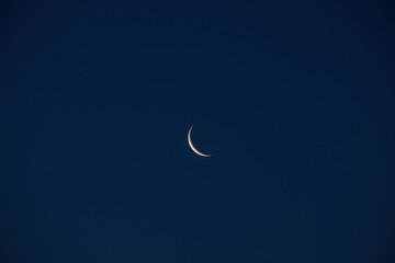 Crescent moon glowing softly against a deep blue night sky with large copy space, creating a peaceful celestial background for astronomy, dreams, spirituality and nighttime concepts © Pihuliak