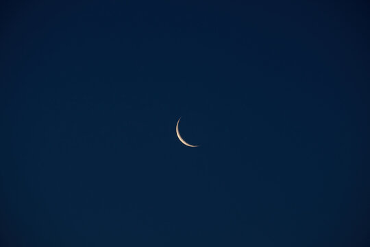 Crescent moon glowing softly against a deep blue night sky with large copy space, creating a peaceful celestial background for astronomy, dreams, spirituality and nighttime concepts