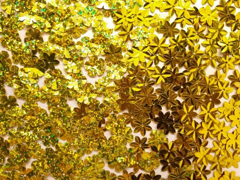 Sparkling golden flower shaped sequins with metallic and glitter textures for craft backgrounds.