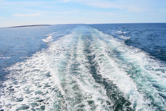 Small waves, a wake, being caused by a traveling boat on the ocean.