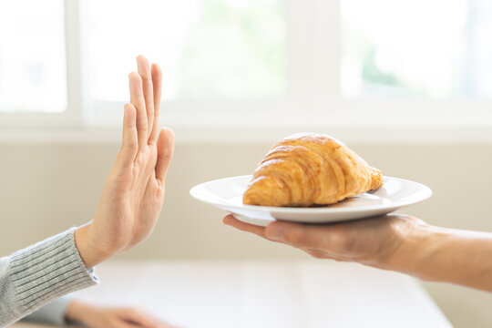 Ketogenic, Low carb, Intermittent Fasting. Diet, refuse woman, girl hand push out, deny butter croissant bread on plate, fighting to keep it from getting fat. Healthy nutrition of weight loss.