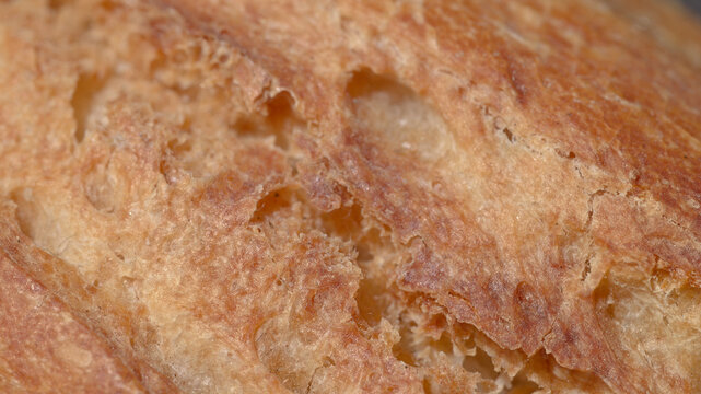 Extreme close up of dry bread roll crust and porous texture