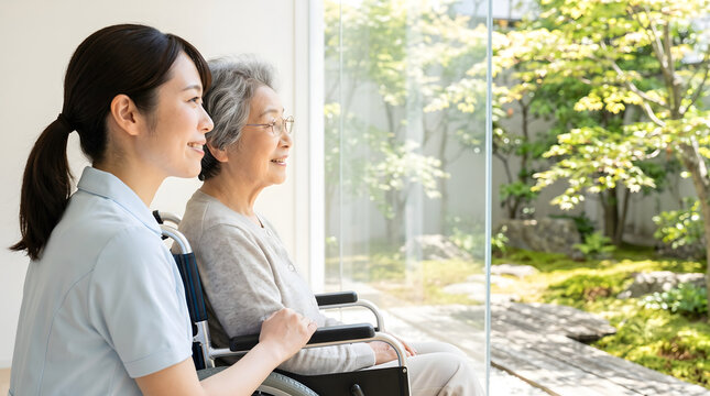 Caregiver and elderly woman in wheelchair enjoying a garden view