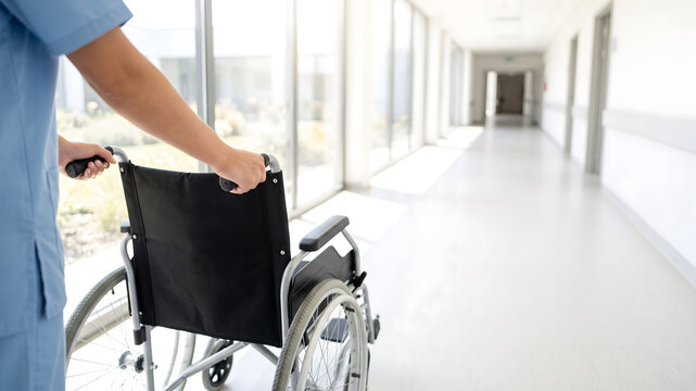 Care worker pushing an empty wheelchair through a bright corridor