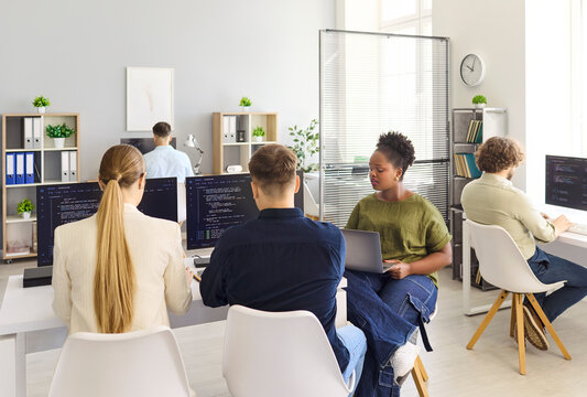 Developers programmers team in office coding. Coworkers use computers with code visible, focusing on collaboration and software development in a technology workspace. Team work idea made clear.