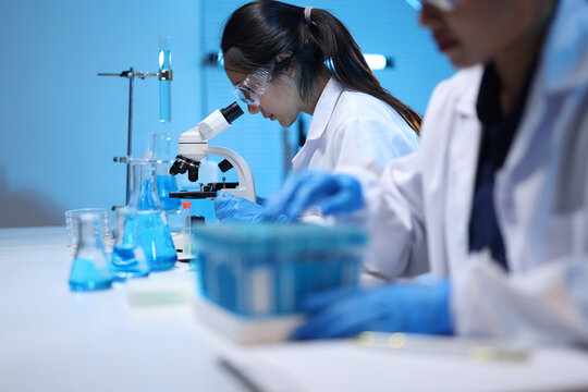 Scientists conducting research with microscope in laboratory.
