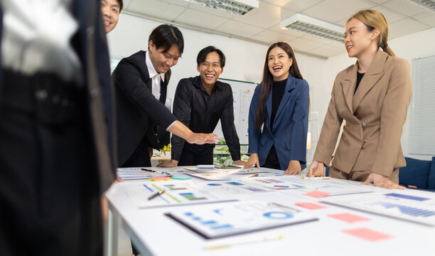 Asian business team collaborating laughing during office meeting.