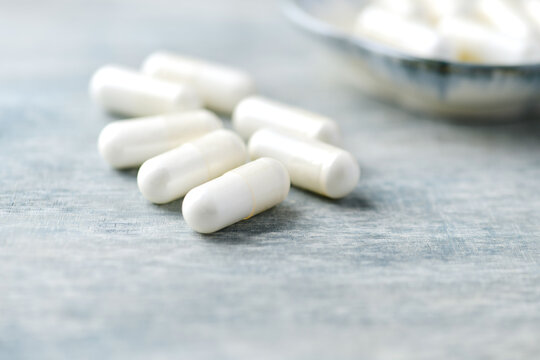 Creatine capsules on wooden background. Soft focus. Close up. Copy space
