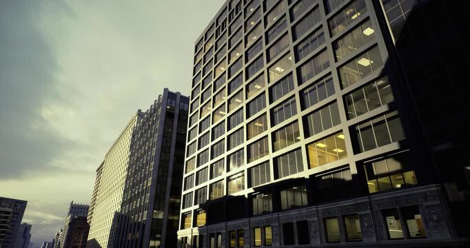 Golden light on contemporary office block, warm reflections illuminate glass and metal facades while corridor of corporate addresses hints at evening commute