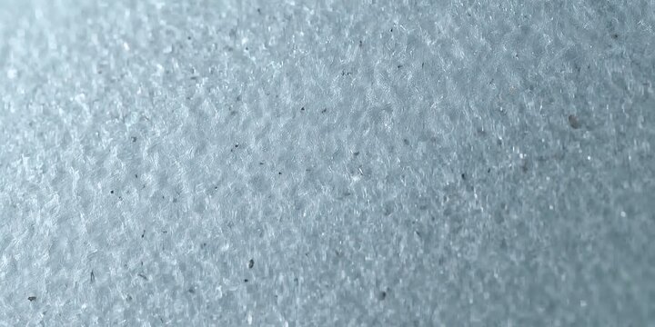 Macro closeup of white textured fabric surface with woven fibers and small dark particles