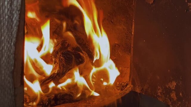 Intense burning of crumpled paper and kindling in the fire inside the cast-iron combustion chamber of the stove