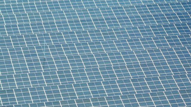 Aerial view of a solar farm on lush green land, showcasing photovoltaic panels, renewable energy, clean electricity and sustainable development for a low carbon modern world. 4k.
