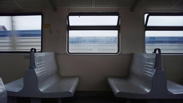 Wide shot inside a moving train at dusk, empty seats, three windows, countryside rolling past. Perfect for travel, journey, and transport themes.