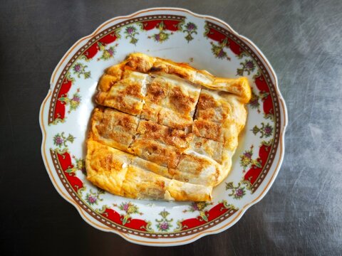 Top View of Pempek Lenggang Panggang, Traditional Palembang Grilled Fish Cake Wrapped in Egg Served on Vintage Plate