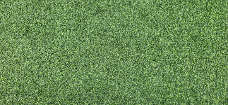Artificial green grass background. Artificial turf high-density dark green. Surface of green synthetic fibers. Made from synthetic fibers, 2 types of plastic, Polyethylene (PE), Polypropylene (PP).
