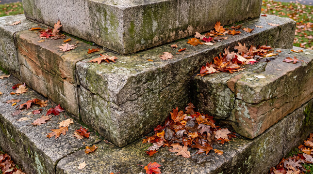 Autumn leaves with rich red and orange colors scattering on the rough surface of an old stone monument, creating a seasonal texture background, ideal for fall themed designs and vintage concepts