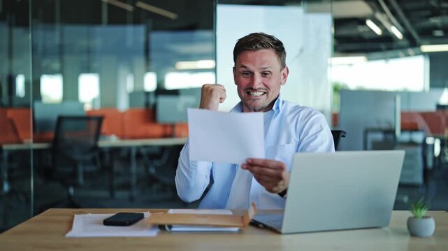 Businessman Celebrates Good News Reading Document in Modern Office